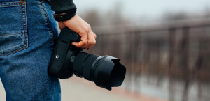Male hands holding professional camera outdoors